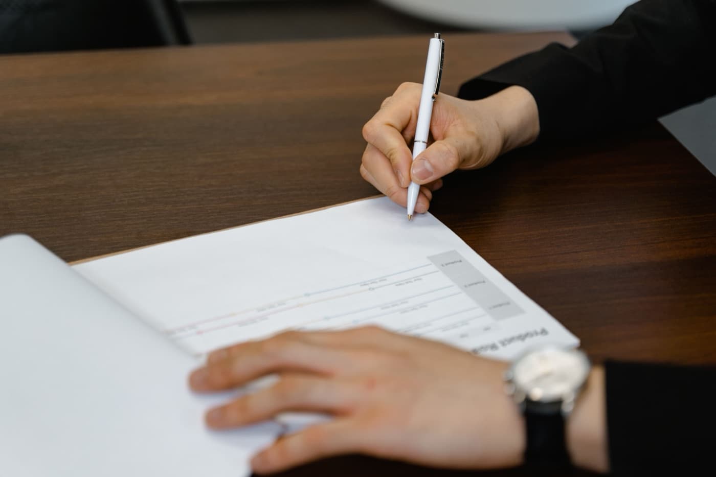 A person signing a printed product documentation sheet at a desk