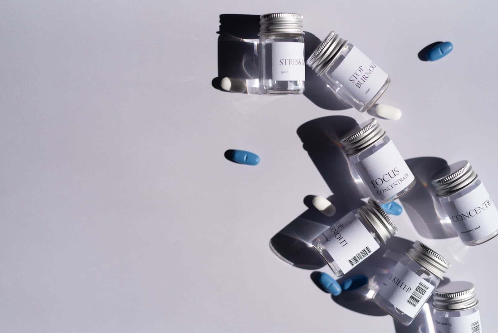Small glass jars labelled STRESS KILLER, STOP BURNOUT, FOCUS and CONCENTRATE floating with pills — the same format under different brand names.