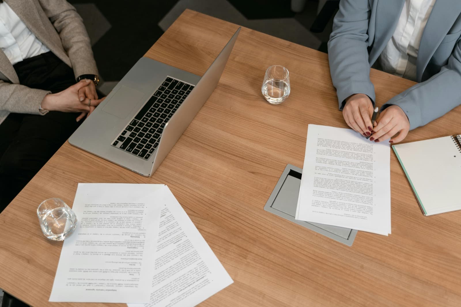 Two professionals reviewing and signing an industrial-chemicals supply contract across a desk, with documents and a laptop.