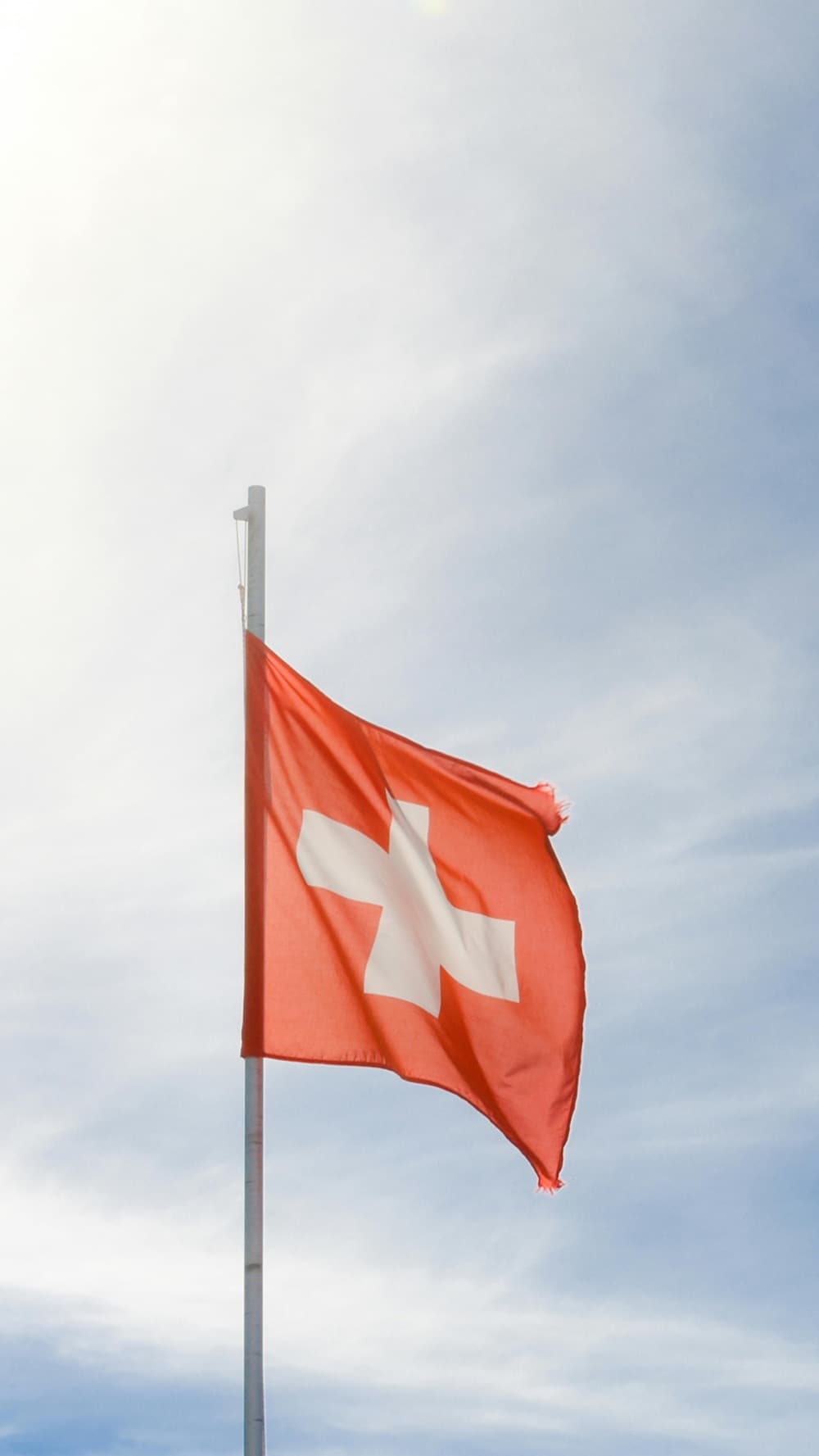 The Swiss flag flying against a bright sky.